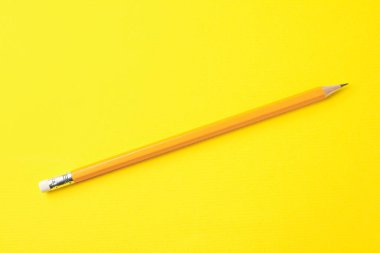 Sarı arkaplanda keskin bir grafit kalem, üst görünümde.