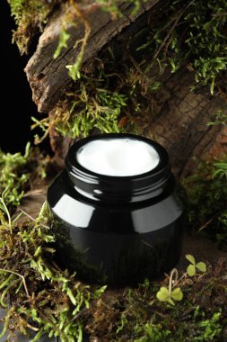 Ağaç kabuğunda bitkilerle birlikte nemlendirici vücut kremi, yakın plan.