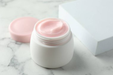 Beyaz mermer masanın üzerinde bir kavanoz nemlendirici vücut kremi, yakın plan.