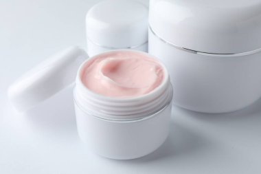 Beyaz arka planda nemlendirici vücut kremi kavanozları, yakın plan.