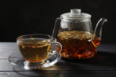 Siyah ahşap masada taze bitki çayı.