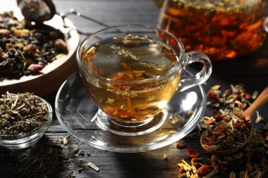 Bitki çayı ve kuru yaprakları siyah ahşap masada serinletiyor.