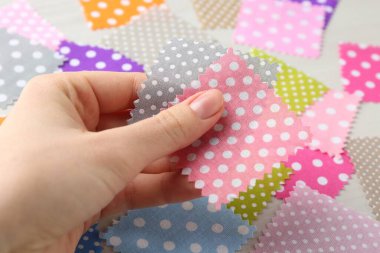 Beyaz ahşap masada farklı kumaşlardan örnekler taşıyan kadın, yakın plan.