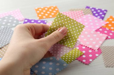 Beyaz ahşap masada farklı kumaşlardan örnekler taşıyan kadın, yakın plan.