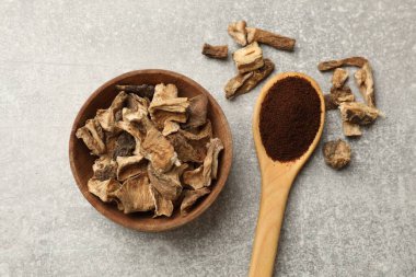 Kuru hindiba kökleri kasede ve kaşıkta toz, gri desenli masa, düz.