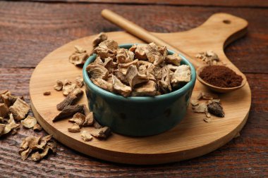 Kuru hindiba kökleri kasede ve kaşıkta, tahta masada toz, yakın plan.