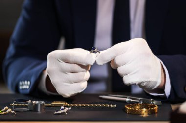 Kapalı bir masada lüks bir yüzükle çalışan bir eksper.