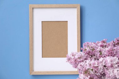 Açık mavi arkaplanda güzel leylak çiçekleri ve resim çerçevesi, yakın plan.