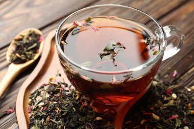 Cam bardakta Aromatik bitki çayı ve ahşap masada kuru yapraklar, yakın plan.