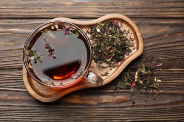 Cam bardakta Aromatik bitki çayı ve ahşap masada kuru yapraklar.