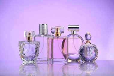 Ayna yüzeyinde mor arka planda parfüm şişeleri