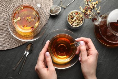 Siyah masada aromatik bitkisel çayı olan bir kadın.