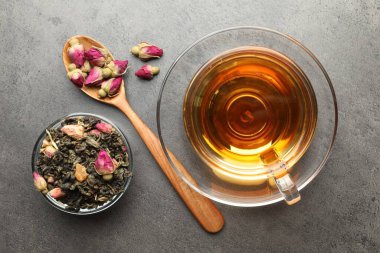 Aromatik bitki çayı, kuru yapraklar ve gri masada çiçekler, düz uzanmış.