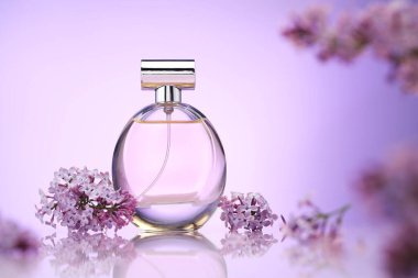 Bir şişe parfüm ve ayna yüzeyinde eflatun rengine karşı leylak çiçekleri, seçici odak