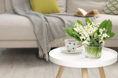 Bir buket güzel vadi zambağı ve bir fincan çay içerideki sehpanın üzerinde. Metin için boşluk