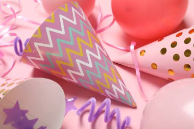 Parti şapkaları ve pembe arka planda şenlikli dekor, düz yatış.