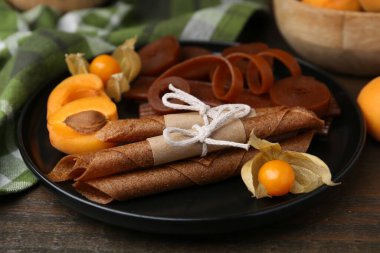 Lezzetli meyve derisi, bitki kökü ve kayısılar ahşap masada, yakın plan.