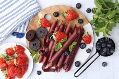 Lezzetli meyve dürümleri, çilekler, yaban mersinleri ve nane şekeri beyaz fayanslı masa, düz yatak