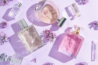 Lüks parfümler ve açık mor arka planda güzel leylak çiçekleri.