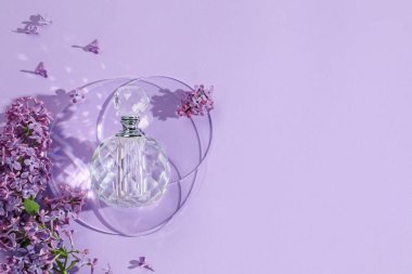 Bir şişe parfüm ve açık mor arka planda güzel leylak çiçekleri. Metin için boşluk