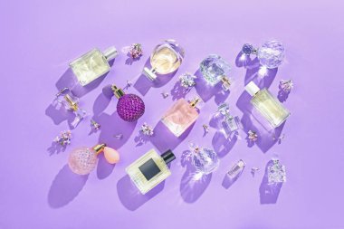 Düz kompozisyon, parfüm şişeleri ve mor arka planda leylak çiçekleri vardı.