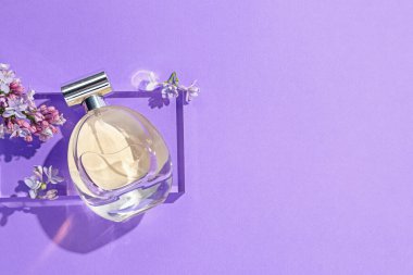 Bir şişe parfüm ve mor arka planda leylak çiçekleri. Metin için boşluk