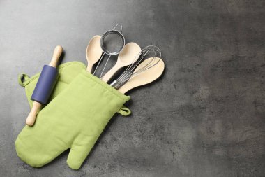 Mutfak aletleri farklı, fırın eldivenleri gri masada, düz yerde. Metin için boşluk