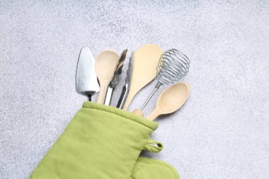 Farklı mutfak gereçleri fırın eldivenleri ışık masasında, üst görünümde.