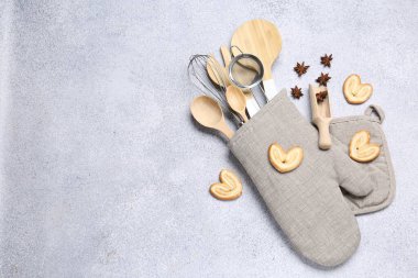 Farklı mutfak aletleri fırın eldivenlerinde, kurabiyeler ve anason yıldızları ışık masasında, düz yerde. Metin için boşluk