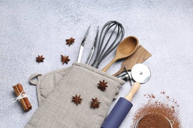 Farklı mutfak aletleri fırın eldiveni, kakao tozu, tarçın ve anason yıldızları ışık masasında, düz yatıyordu.