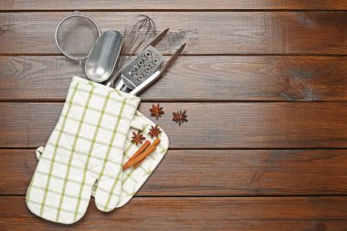 Farklı mutfak aletleri fırın eldiveni, tarçın ve ahşap masa üzerinde anason yıldızları, düz yatak. Metin için boşluk
