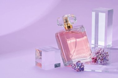 Mor arka planda parfüm şişesi ve leylak çiçeklerinin şık sunumu, yakın plan. Metin için boşluk