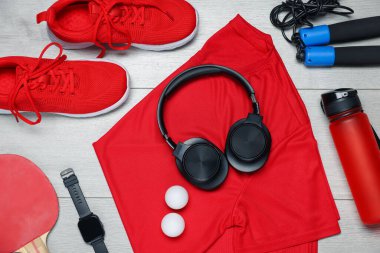Spor kıyafetleri ve yerde kulaklıkları olan düz bir kompozisyon.