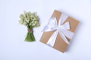 Güzel vadi zambağı çiçekleri ve beyaz arka planda bir hediye.