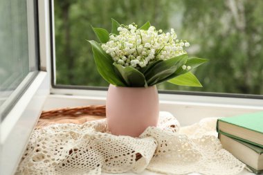 Vazodaki nilüfer çiçekleri ve içerideki pencere kenarındaki kitaplar.