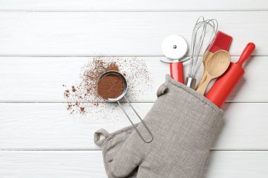Farklı mutfak aletleri fırın eldiveni ve beyaz ahşap masa üzerinde tarçın, düz yatak. Metin için boşluk