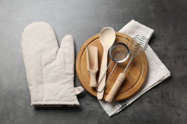 Mutfak aletleri ve fırın eldivenleri gri masada, düz yerde.