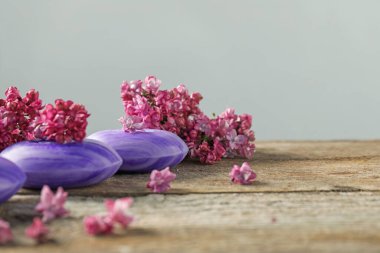 Sabun çubukları ve ahşap masadaki leylak çiçekleri gri arka planda, yakın plan. Metin için boşluk