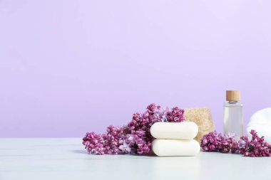Sabun çubukları, esaslı yağ ve leylak çiçekleri beyaz mermer masa üzerinde mor arka planda. Metin için boşluk