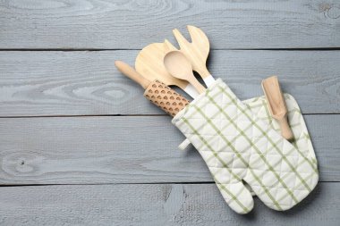 Fırın eldivenindeki farklı mutfak aletleri açık gri ahşap masa, üst manzara. Metin için boşluk
