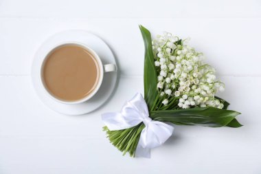 Bir buket güzel vadi zambağı çiçekleri ve beyaz ahşap arka planda kahve.
