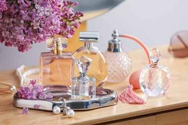 Parfüm şişeleri, aksesuarlar ve ahşap masada leylak çiçekleri.
