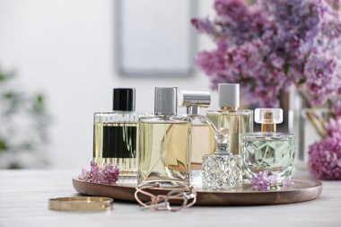 Beyaz ahşap masada parfüm şişeleri ve leylak çiçekleri.