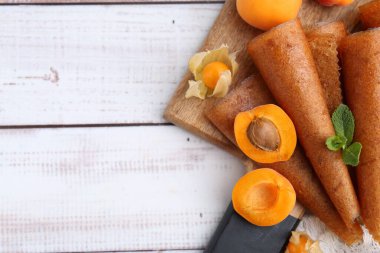 Lezzetli meyve dürümleri, kayısılar ve beyaz ahşap masa üzerinde bitki salatası, düz yatak. Metin için boşluk