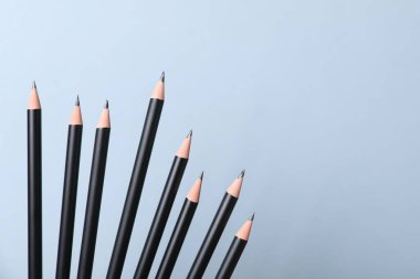 Açık gri arka planda birçok keskin grafit kalem, yakın plan. Metin için boşluk