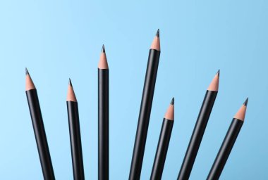 Açık mavi arkaplanda birçok keskin grafit kalem, yakın plan