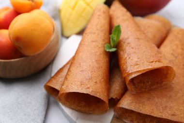 Lezzetli meyve dürümleri, nane, mango ve kayısılar masada, yakın plan.