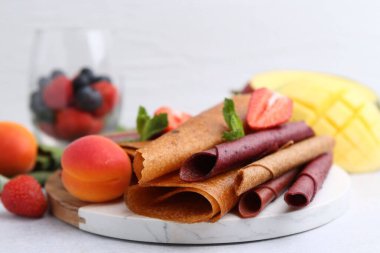 Lezzetli meyve dürümleri, nane, kayısı ve böğürtlen ışık masasında, yakın plan.