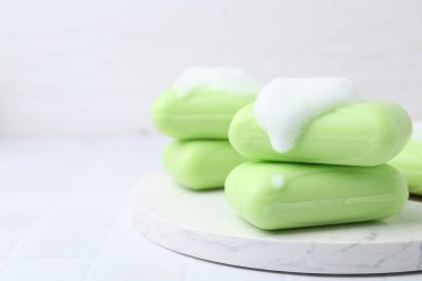 Beyaz masadaki köpüklü sabun çubukları, yakın plan. Metin için boşluk