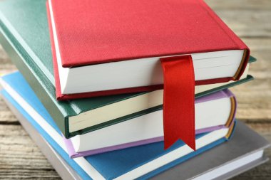 Kırmızı kurdele yer imi ve ahşap masa üzerinde renkli kitap, yakın plan.